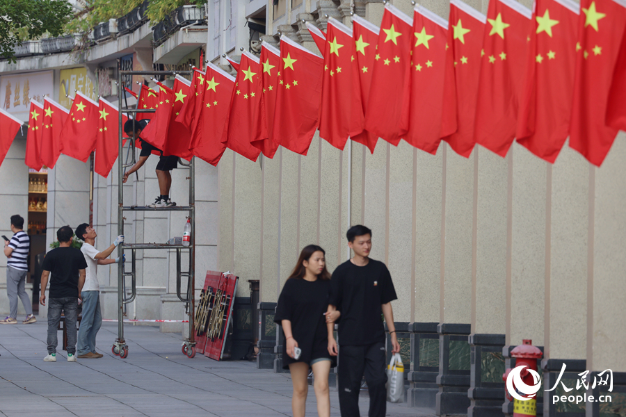 工作人员将一面面五星红旗整齐有序地插上骑楼。人民网记者 陈博摄